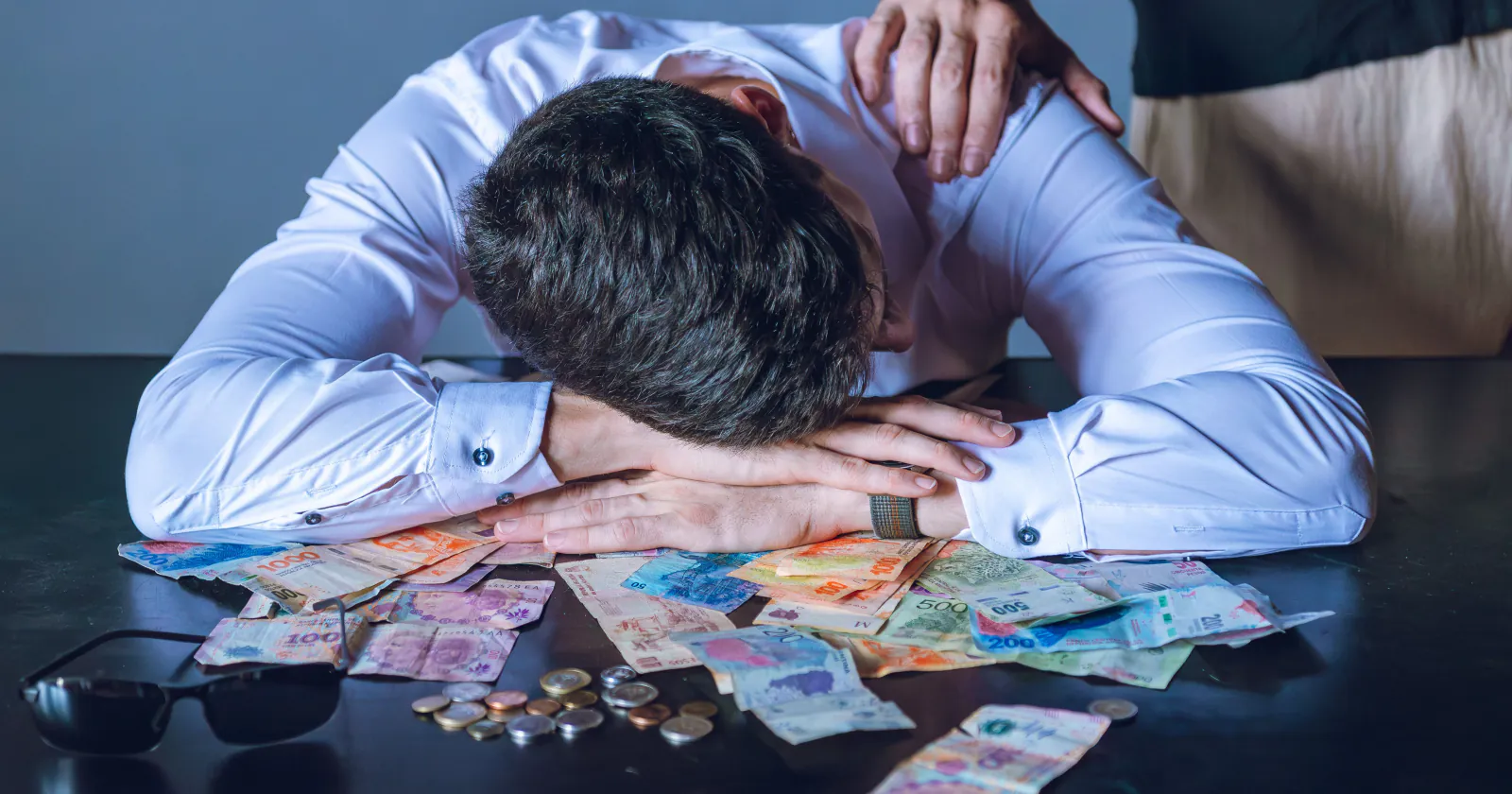 Trabajador con la cabeza baja rodeado de billetes tras firmar su renuncia